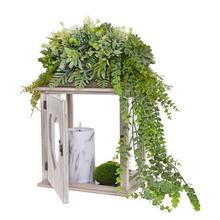 Smútočná väzba s dekoratívnymi rastlinami a sviečkou.