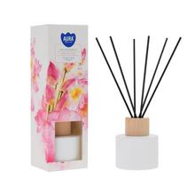 Difuzér s lotosovým květem v bílé lahvi a černými tyčinkami.