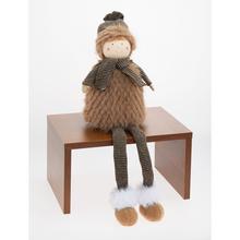 Textilní dekorace chlapce sedícího v hnědo-bežových barvách.