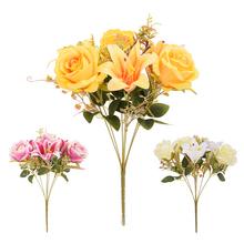 Kytice umělých květin s růžemi a lilie v žlutých a růžových odstínech.