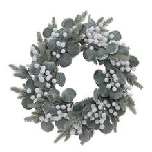 Vánoční věnec s cesmínou, eukalyptem a bílými bobulemi, zasněžený.