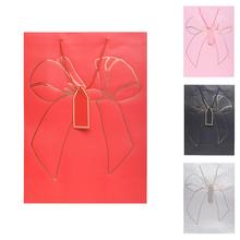 Dárková taška s mašlí v různých barvách.