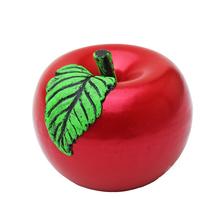 Červená svíčka ve tvaru jablka se zeleným listem.